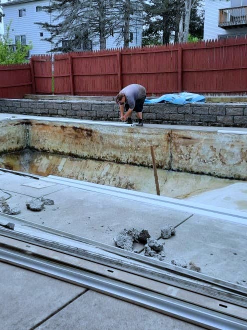 Pool before: gutted shell with rusted walls and coping rails removed