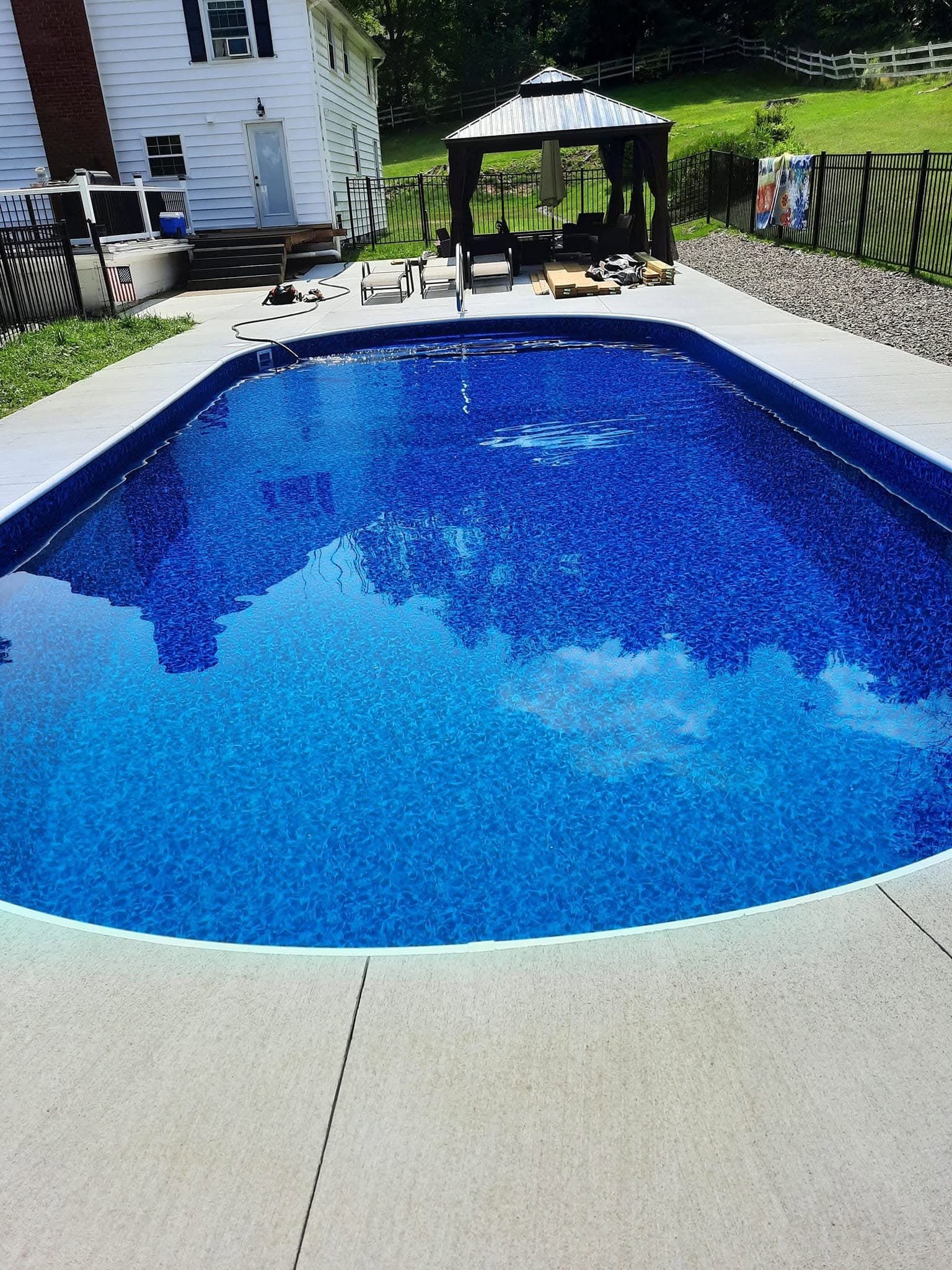 Pool after: completed rebuild with new liner and deep blue water from the same viewpoint