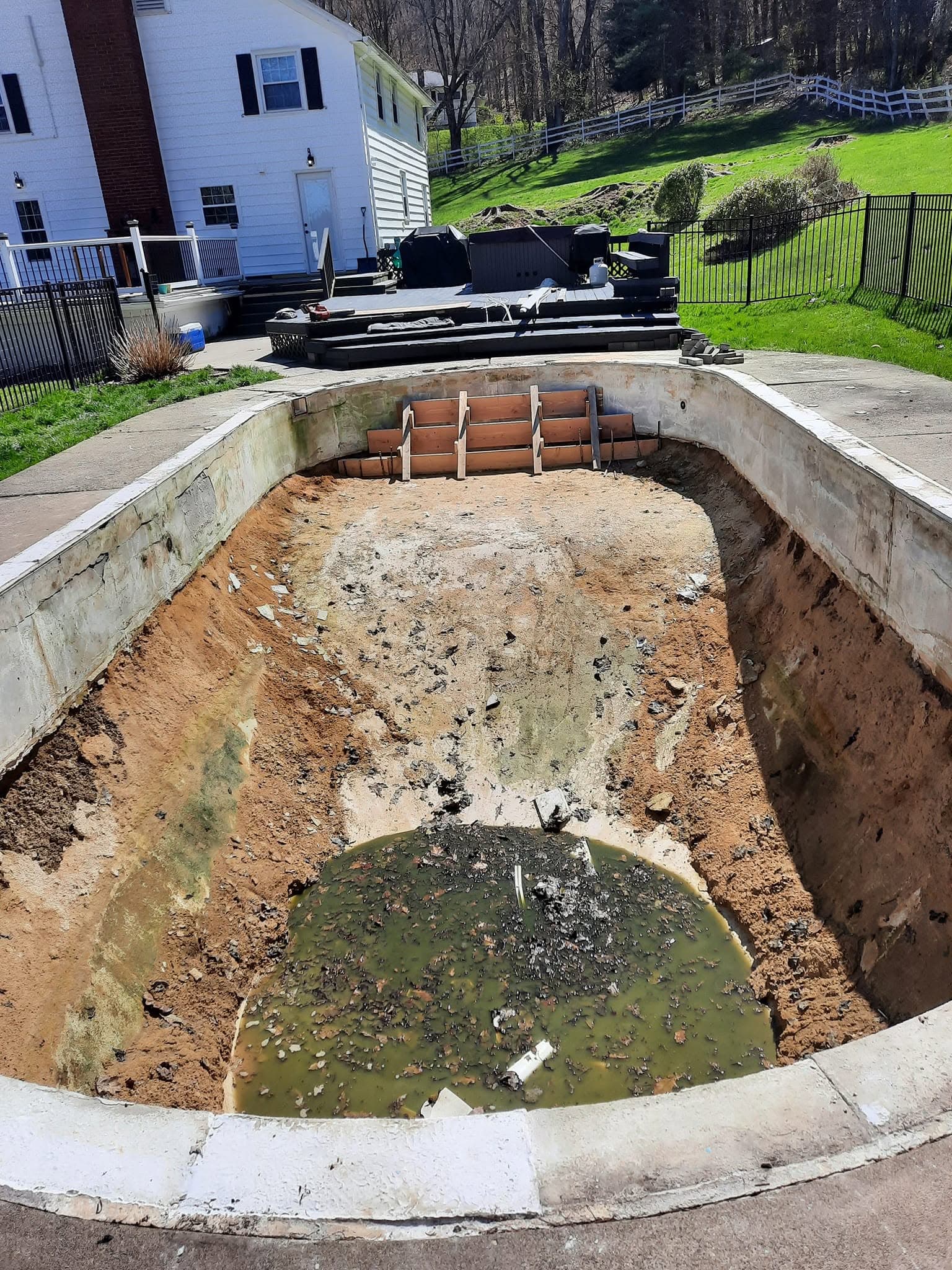 Pool before: completely gutted shell down to bare dirt with murky runoff in the deep end