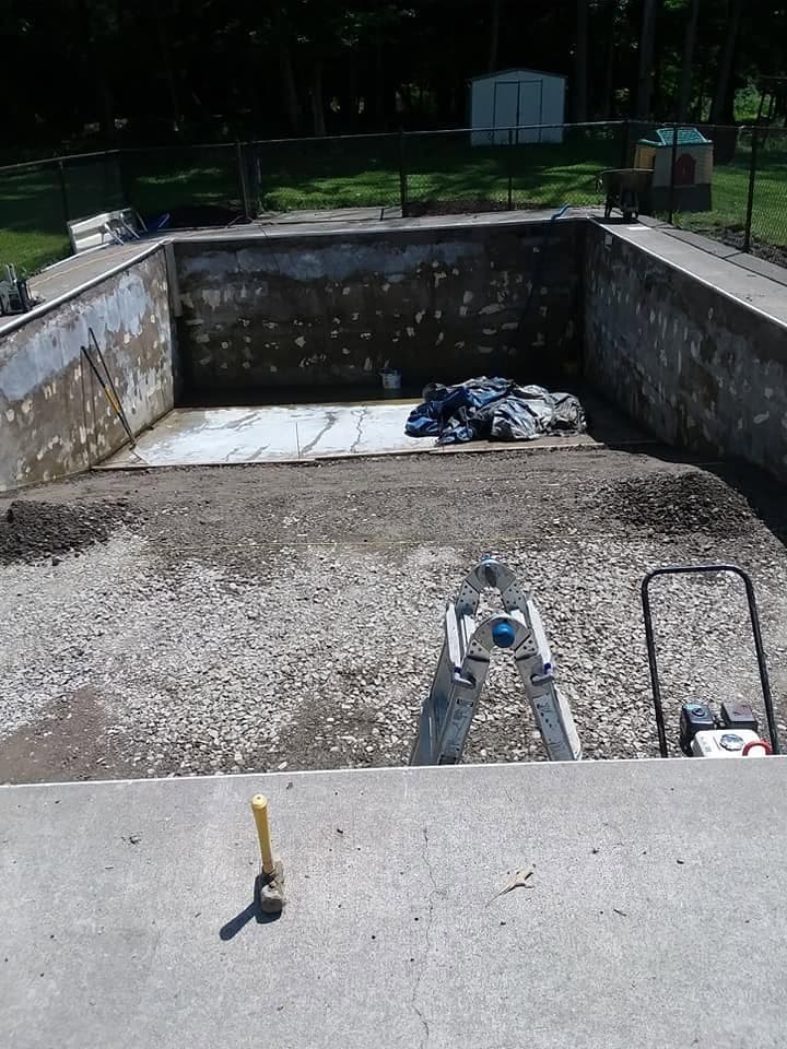 Pool before: gutted shell with stripped walls and a bare gravel base