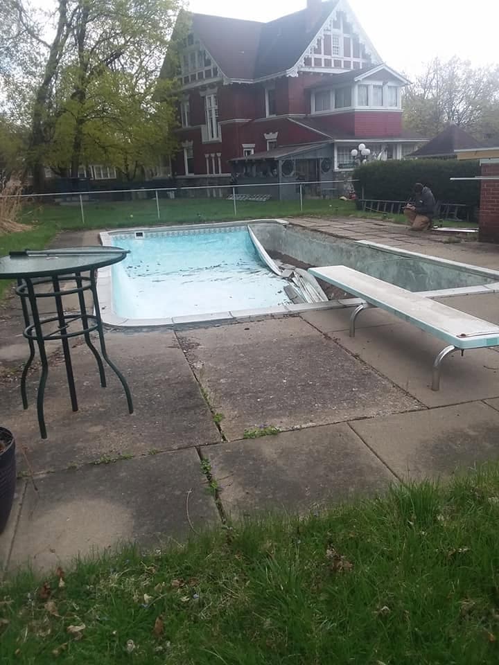 Pool before: drained pool with a torn liner and cracked, weedy flagstone deck