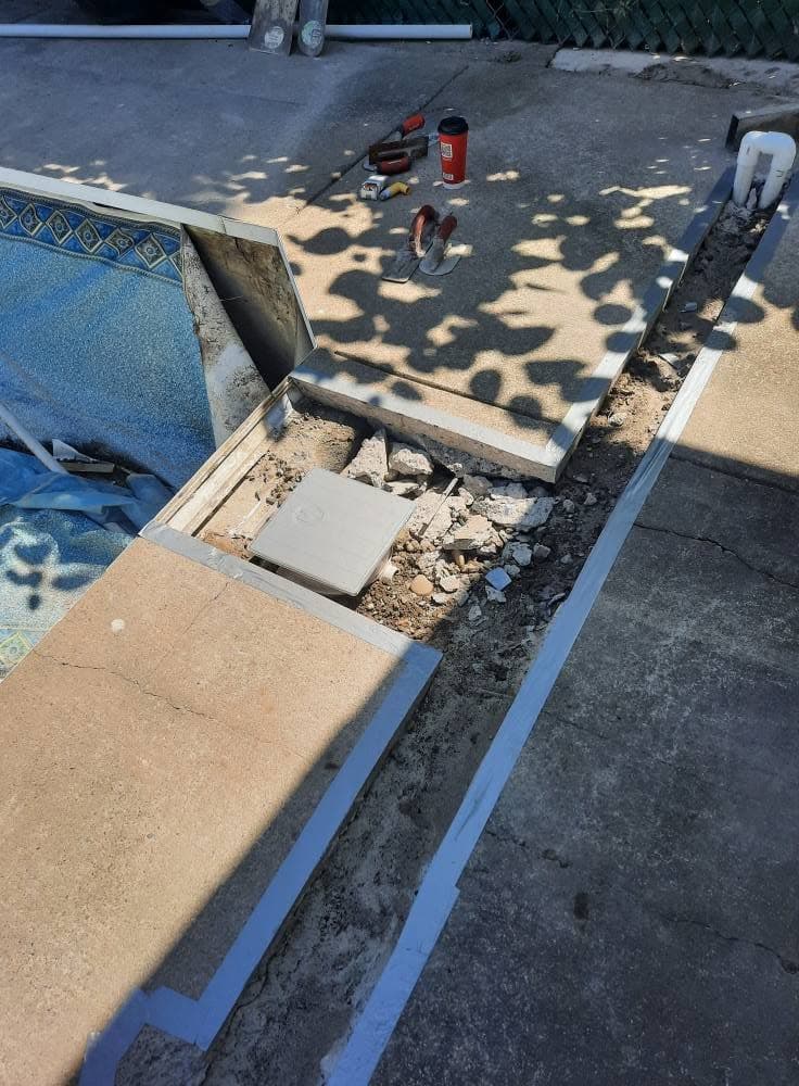 Trench with new underground pool plumbing beside the coping