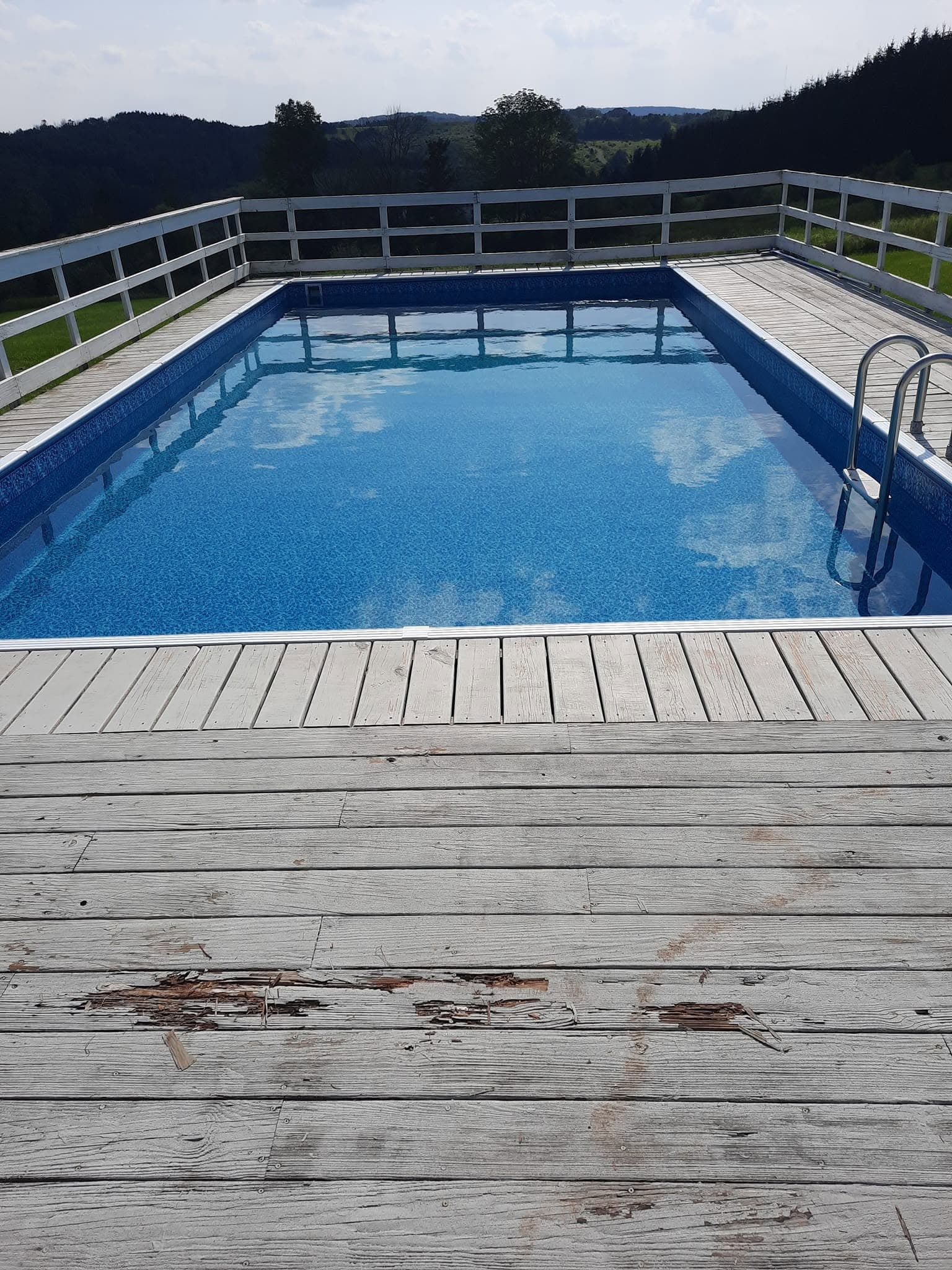 Pool after: new liner and clear blue water with hilltop views beyond the deck